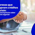 Empresas que compram créditos judiciais: negociação de RPV e precatórios com aperto de mãos sobre mesa de trabalho com notebook e documentos